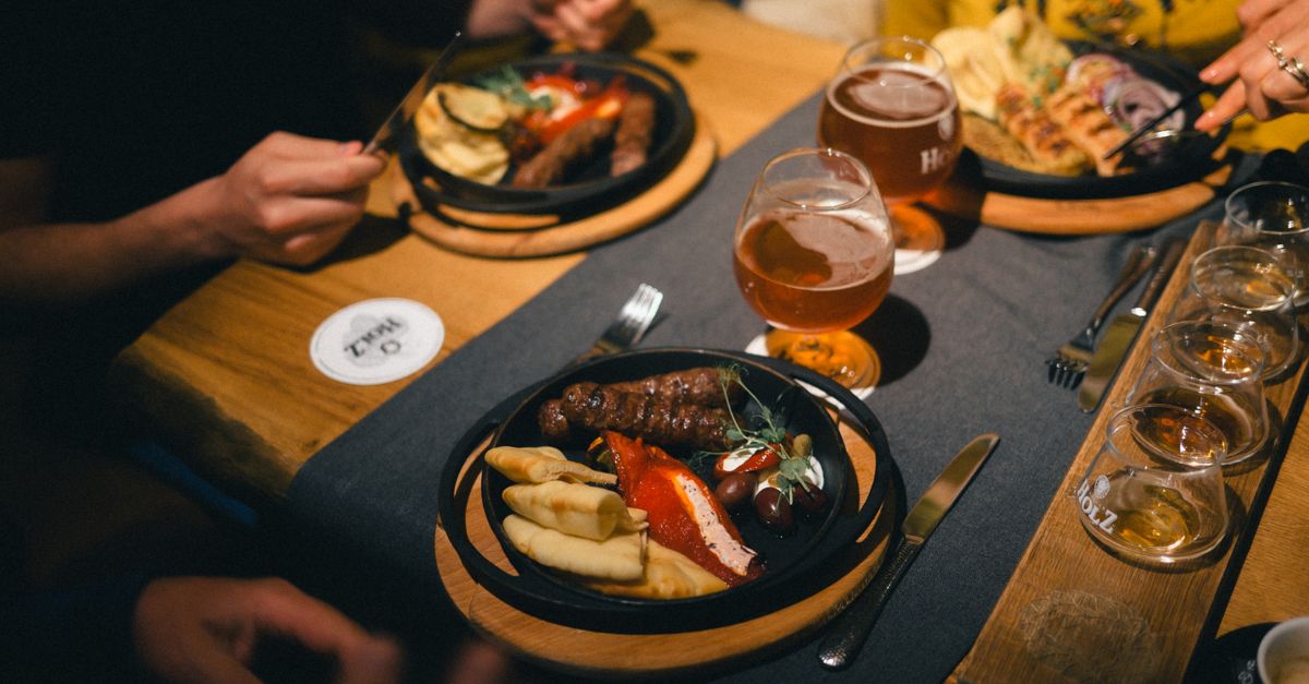 Friends sharing plated gastropub dishes and craft beer at a candlelit table