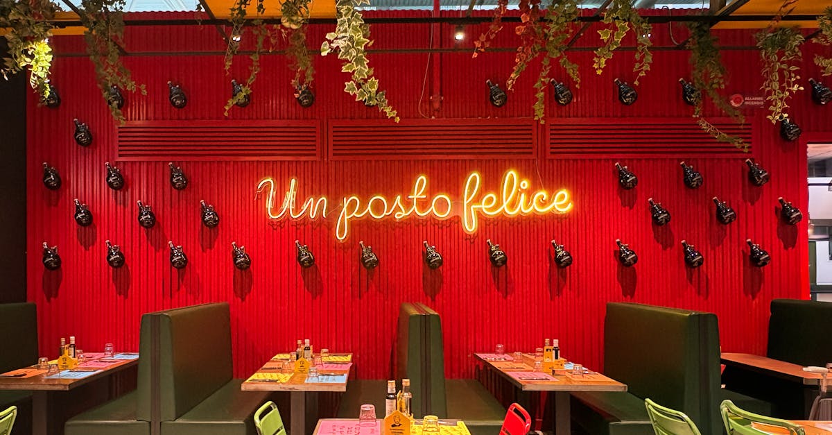 The dining room of a modern Italian restaurant with booth seating and a neon sign