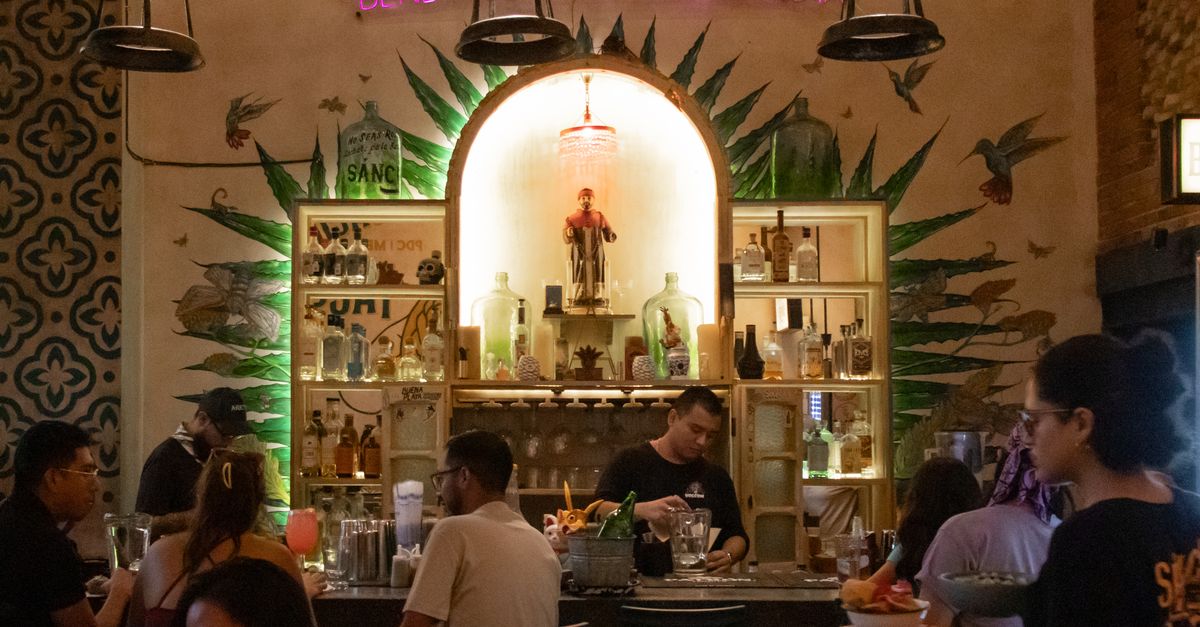 A warmly lit Mexican cantina interior with a tequila bar and guests