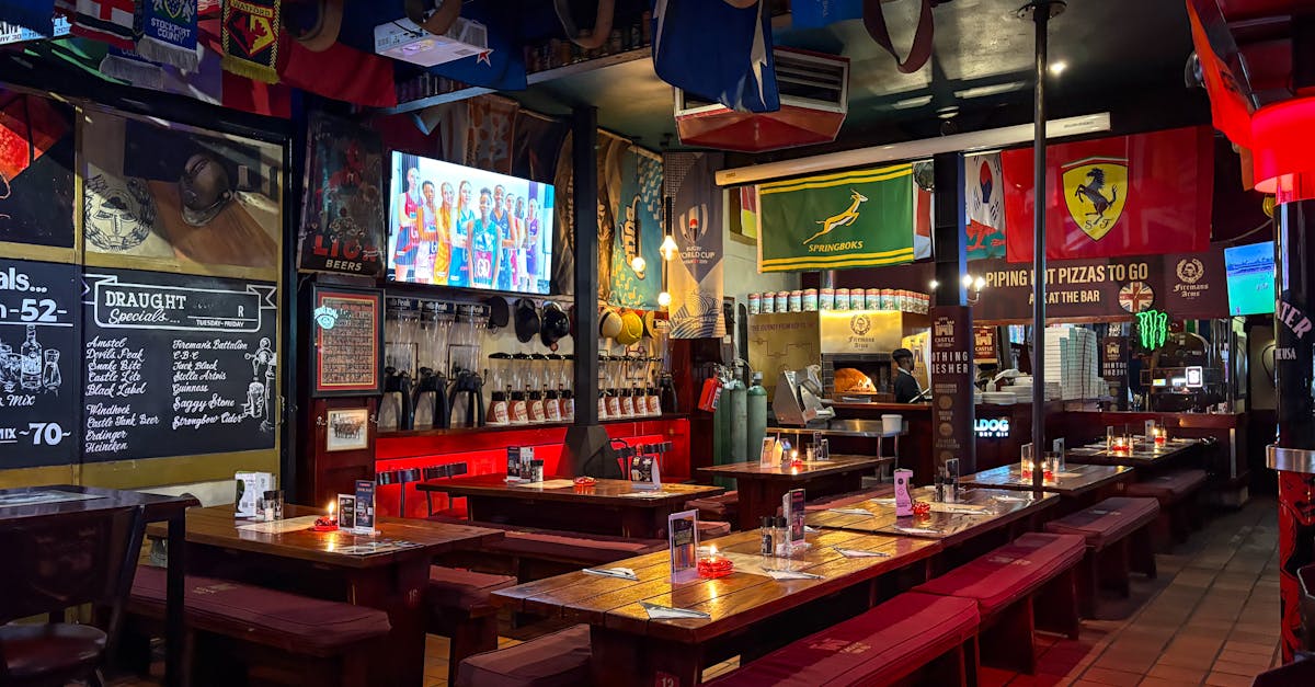 A lively sports bar interior with big screens, flags and long benches