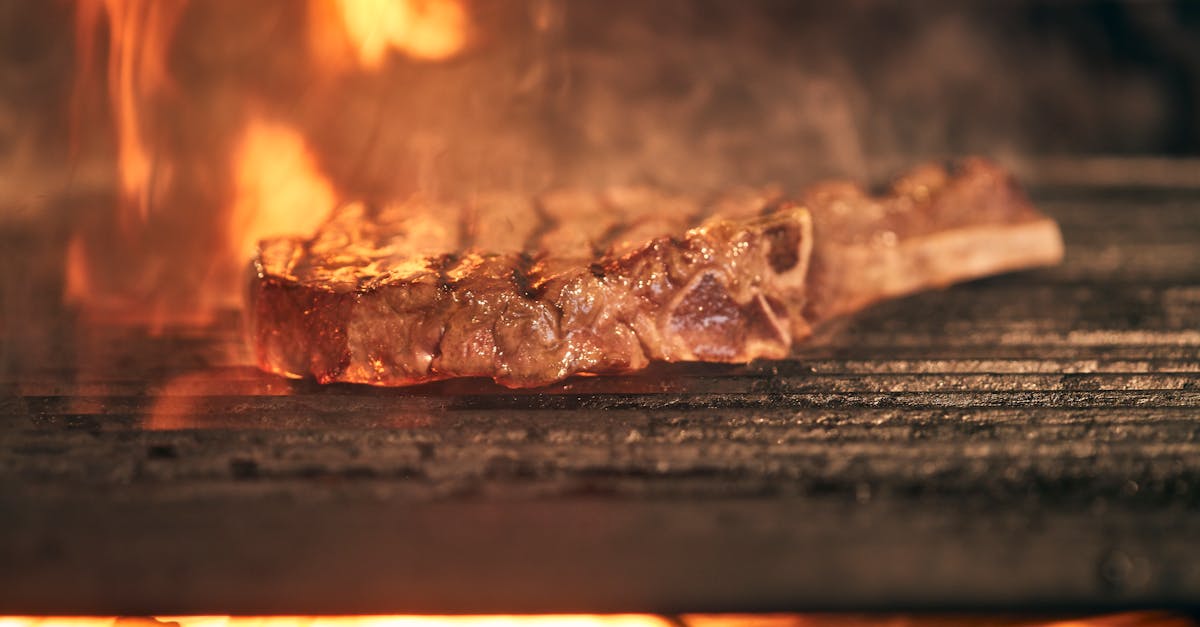 A prime steak searing over an open flame on a steakhouse grill