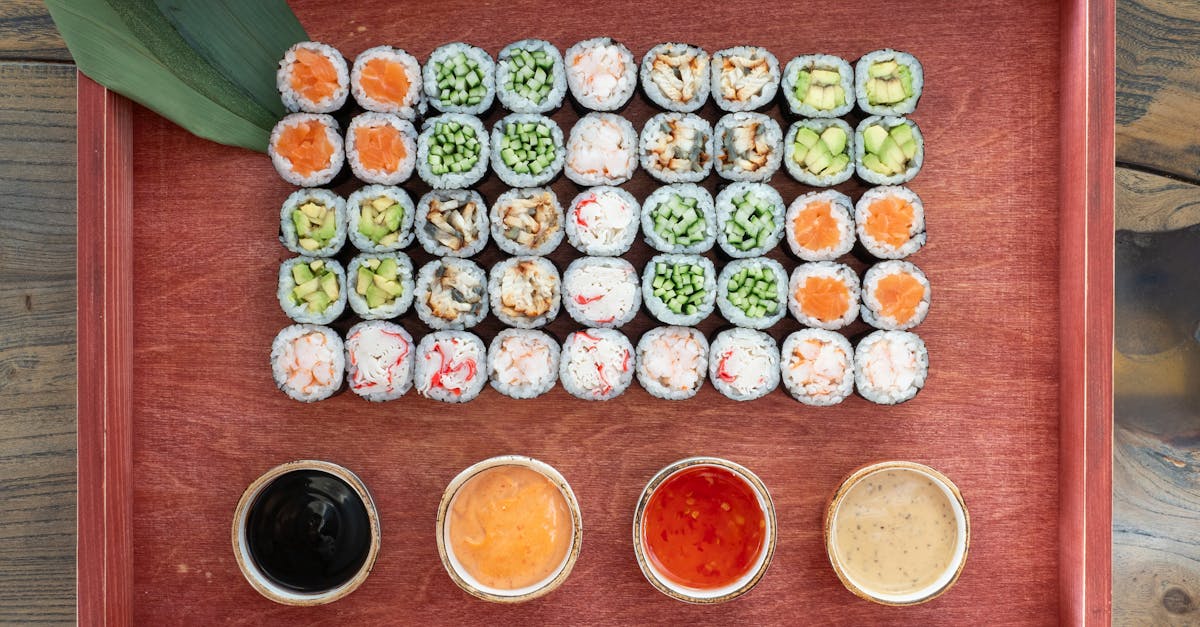 A platter of assorted sushi and maki rolls with dipping sauces on a wooden tray