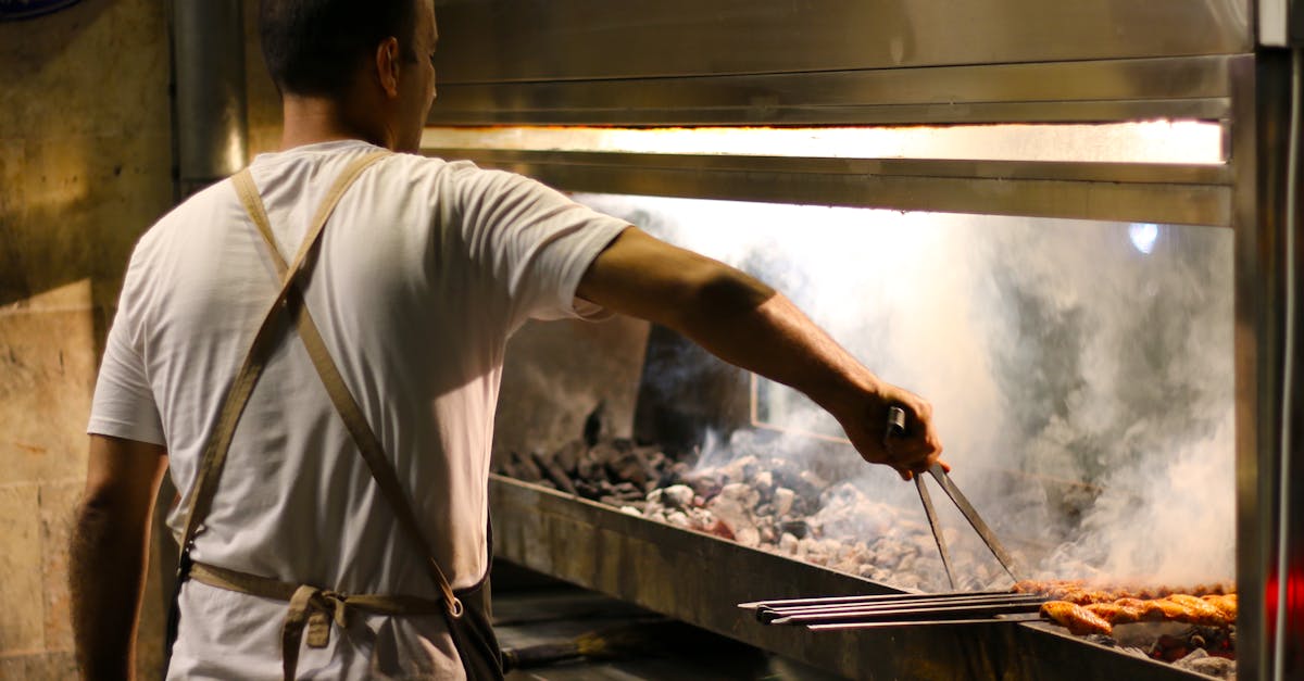 A chef grilling skewers over a charcoal ocakbaşı in a Turkish grill house
